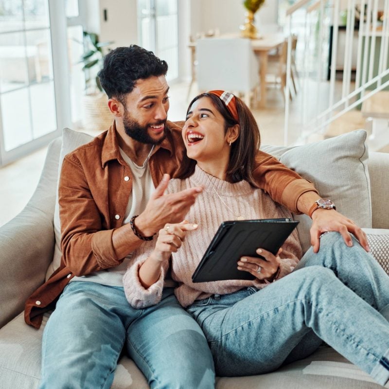 home,,funny,and,couple,on,sofa,,tablet,and,bonding,together